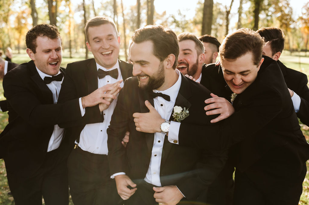 “Groom Zach laughing with groomsmen on a crisp fall wedding morning | relaxed documentary wedding photography.”