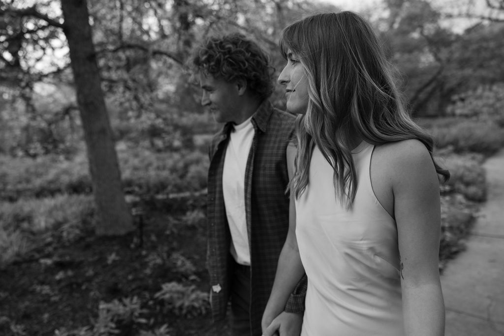 Couple walking through a lush garden surrounded by vines during their Arizona engagement session, captured in a filmy documentary style.
